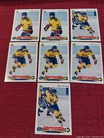 Seven Upper Deck hockey cards from the Sweden World Junior Tournament team 1992/1993 arranged on a red surface. Cards show players Markus Naslund (2 cards), Mikael Nylander (2 cards), and Peter Forsberg (3 cards) in Swedish national team uniforms.