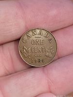 Reverse side of the 1934 Canadian one cent coin showing denomination, maple leaves, year and country name.
