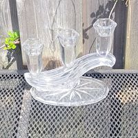 Crystal 3-arm candleholder placed on outdoor metal surface showing the side view and base pattern.