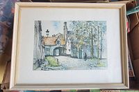 Framed picture showing quaint village street with buildings, trees, and lamp post.