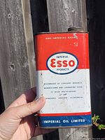 Front angle close-up of the vintage oil tin with Esso branding and worn red, white, blue paint.