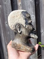 Side view of the signed soapstone carving showing the detailed beard, ear, and textured hair