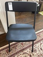 Front view of a single black plastic folding chair showing seat and backrest.