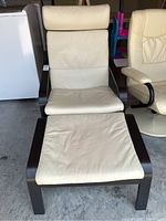 Front view of white leather chair with foot rest on concrete floor.