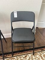 Front view of a gray cloth folding chair showing patterned upholstery and black metal frame