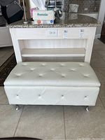 Front view of white leather blanket chest with tufted rhinestone detailing and metal legs.