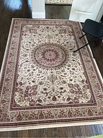 Full view of the ornate rug laid on wooden floor, showing its rectangular shape and medallion center