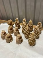 View of all 10 beeswax candles showing six pinecone shaped and four animal shaped candles on white surface.