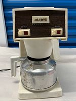 Front view showing the 1970s Mr. Coffee machine with woodgrain front panel and toggle switches