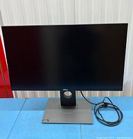 Front view showing monitor on stand with power cable looped next to base