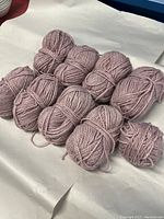12 skeins of mauve pink yarn arranged on white paper, showing overall lot contents