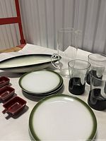 Photo showing green ombré edged side plates, clear glass pitcher, Corning black base glasses, small red square dishes, and oval serving dish.