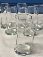 Six clear glass tumblers arranged together, showing their horn shape and slight asymmetrical curves.