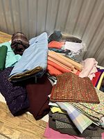Fabric assortment on table showing a variety of cotton fabrics in different colors, patterns, and states of use