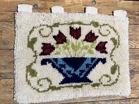 Top view of the embroidered latch hook carpet showing the floral tulip motif in a blue vase on cream background.