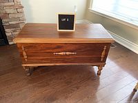 Closed cedar chest/blanket box showing detailed front panel, turned legs and handles. Rich wood finish.