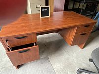 Desk with wood finish, drawers on each side with black handles, and a cable management hole on top.