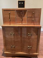 Front view of mid-century modern wooden dresser with 10 drawers, curved front lower drawers, and brass pulls on all drawers