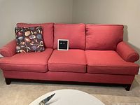 Front view of full sofa showing three seat and back cushions with one floral throw pillow