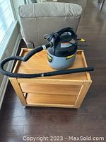 Stinger WD20200 shop vacuum placed on a small wooden cart with hose attached and extension wand alongside.
