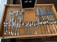 Photo showing layout of forks, spoons, and knives arranged on wooden surface, showing the quantity and style of the vintage Community Plate silverplate cutlery set.