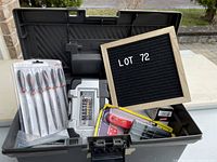 Grey plastic toolbox open showing assorted tools inside including files, Master Mechanic set, red screwdriver and small boxed tools