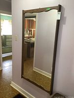 Full view of rectangular wall mirror with faux wood frame hanging on wall, showing size and shape.