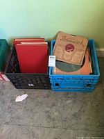 Two crates filled with vintage records in sleeves, some sleeves branded (Portsmuirk, Decca, Columbia) and some plain red or black.