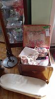 Open vintage wooden sewing box showing sewing notions such as fabric, pincushion, and packaged needles