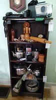 Front view of a four shelf wooden unit containing various kitchen and household items including kettles, wooden utensils, a telephone, and a radio. The unit shows scratches and wear as described by seller.