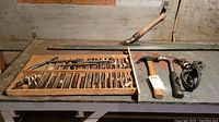 Photo of wooden tray with taps and dies alongside two hammers and a coiled electrical cord on a workbench.