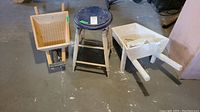 Photo showing two wooden garden wagons and one round wooden stool on a concrete floor.