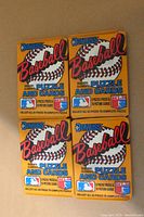 Four unopened 1987 Donruss Baseball wax packs arranged front side up, showing the pack design with Roberto Clemente puzzle and card markings.