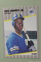 Front side of the 1989 Fleer Ken Griffey Jr rookie card showing the player in Seattle Mariners uniform holding a bat with gray background and card details.