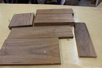 Six rectangular walnut wood pieces arranged on a table, showing different sizes and natural grain patterns.