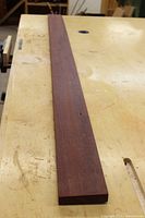 Purple Heart hardwood board lying flat on a workbench, showing grain and color, planed two sides