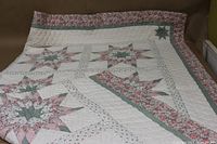 Full view of the quilt showing star pattern with floral and polka dot fabrics in pink, green, and white.