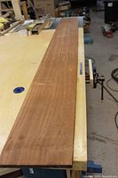 Top face of the mahogany board showing straight, flat ribbon grain on a workshop bench.