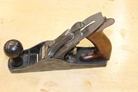 Side profile showing vintage Stanley #3 hand plane with wooden handle and knob, visible chip on handle top, and cast iron body.