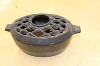 Cast iron stove top humidifier showing top lattice surface and water fill hole, used condition with slight rust spots.