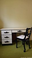Front view of vintage desk with drawers and black chair on wheels with beige upholstered seat