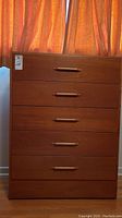 Front view of the teak wood dresser showing all five drawers with wood handles.