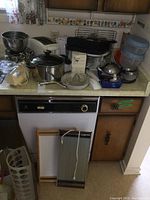 Full countertop view showing most kitchen ware including pots, glass juicer, electric appliances, storage containers, metal racks, and a frying pan.