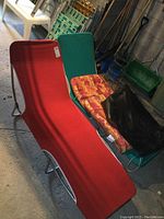 Pair of fabric canvas loungers with metal frames, red and green color, shown with cushion and black storage bag.
