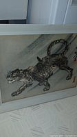 Framed tiger print artwork placed on floor showing full artwork and frame.