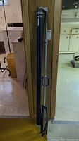 Photo of folded blue projector screen with metal frame and tripod base standing vertically against a wooden surface in basement.