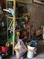 Full view of yellow metal shelf stocked with assorted gardening supplies and tools