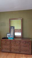 Frontal view of dresser with mirror on top with assorted items on the dresser surface. Shows overall appearance and drawer configuration.