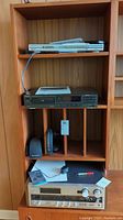 Full view of cabinet shelf holding the Technics CD player, Sony receiver, and Sennheiser headset base with headset, remote, and cables.