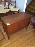 Front view of closed teak cabinet showing two sliding doors and recessed handles